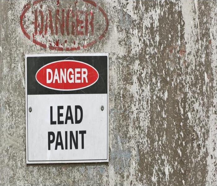 wall covered in flaking lead paint and a danger sign