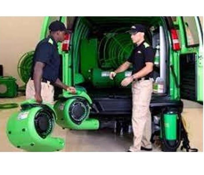 two SERVPRO techs loading air movers into a van
